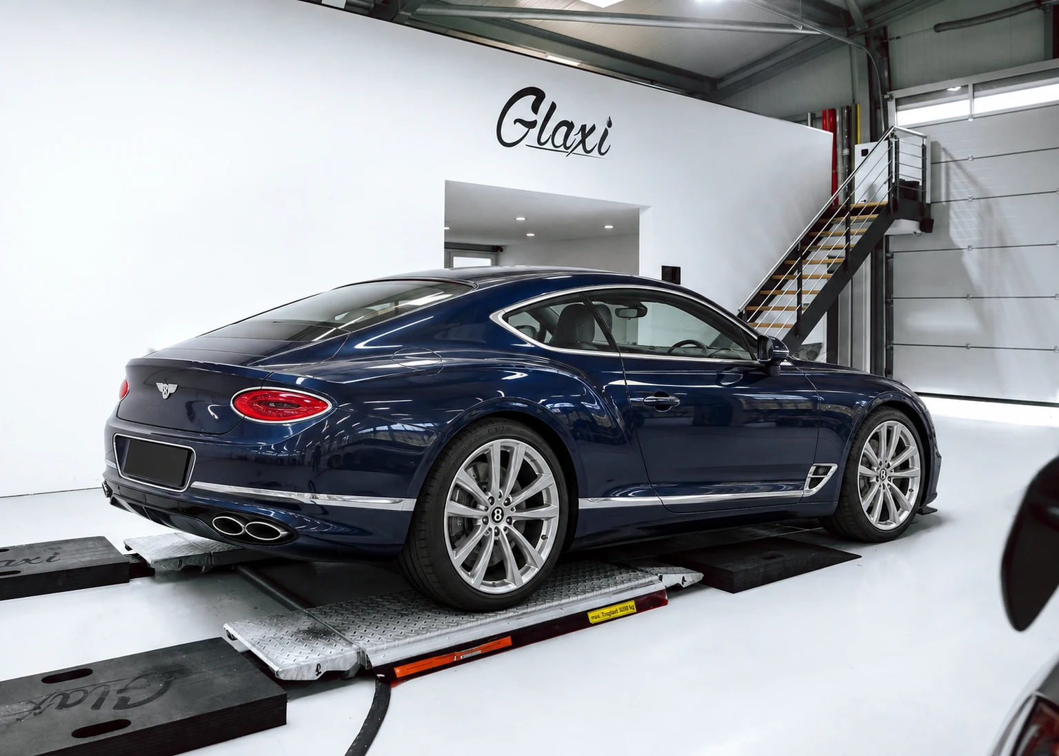 KI-Visualisierung: Heckansicht eines dunkelblauen Bentley Continental GT in einer an die GLAXI-Halle angelehnten Werkstatt