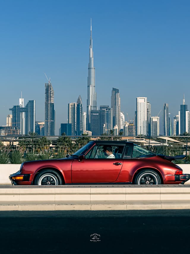 Roter klassischer Porsche 911 Targa in Seitenansicht vor der Skyline von Dubai