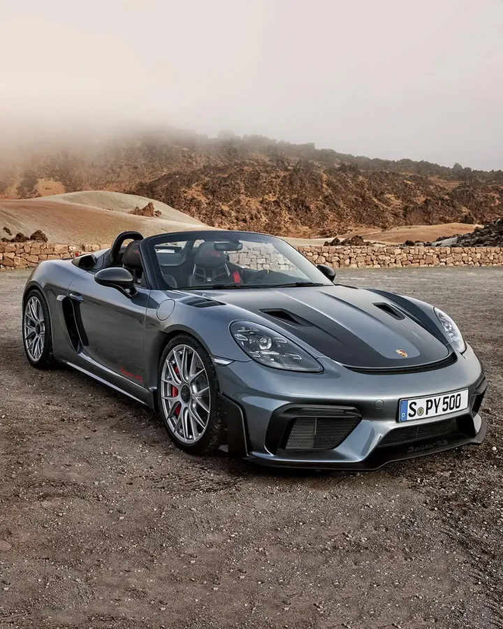 Offener grauer Porsche 718 Spyder RS vor einer steinigen Berglandschaft und tiefen Wolken