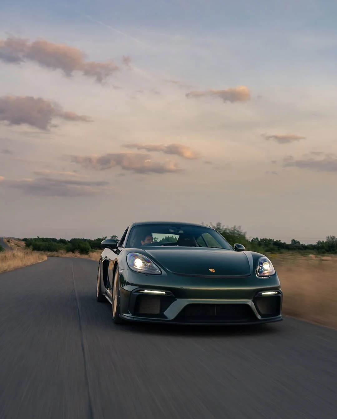 Dunkelgrüner Porsche 718 Cayman GT4 auf einer Landstraße in Oxfordshire im Abendlicht. Originalfoto von @danbrydgess.