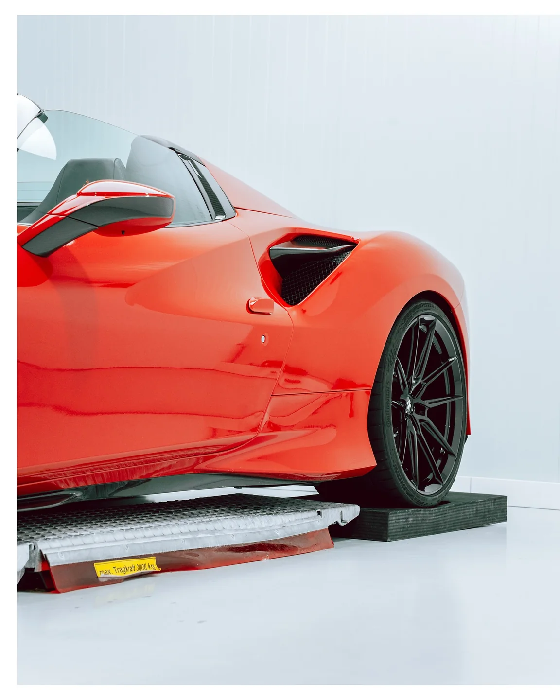 Rote Tür, seitlicher Lufteinlass und Hinterrad des Ferrari F8 Spider auf der Hebebühne