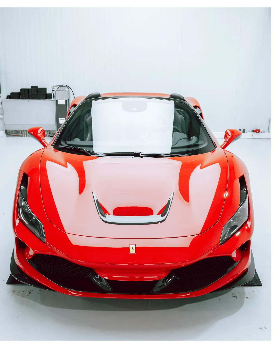 Frontalansicht des roten Ferrari F8 Spider mit geöffnetem Dach in der Werkstatt