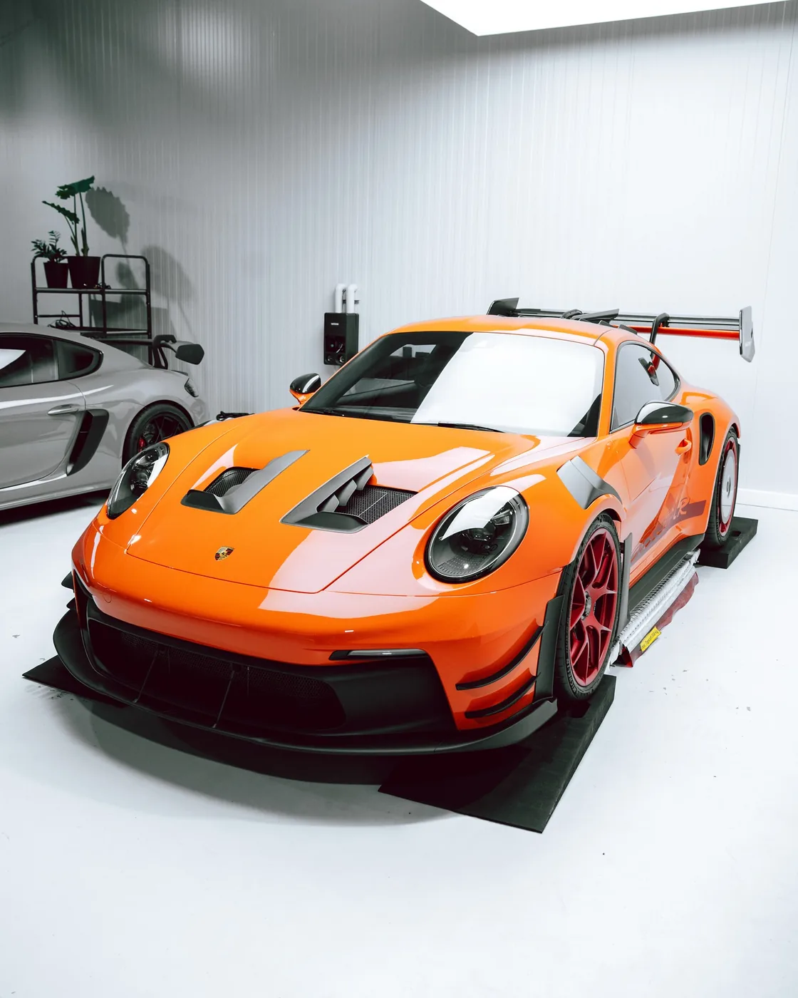 Orangefarbener Porsche 992 GT3 RS Manthey auf der Hebebühne in der neuen GLAXI-Halle in Schwäbisch Hall