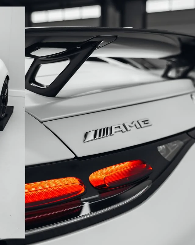 AMG-Schriftzug, schwarzer Heckflügel und leuchtende Rückleuchte am weißen Mercedes-AMG GT 63 S