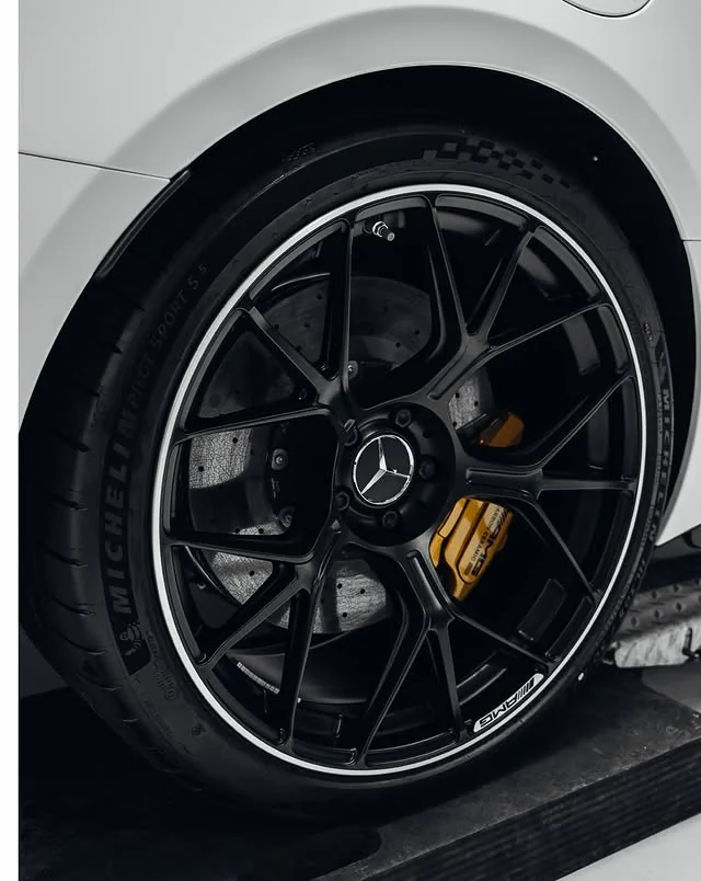 Schwarzes Vielspeichenrad mit gelbem Bremssattel am weißen Mercedes-AMG GT 63 S