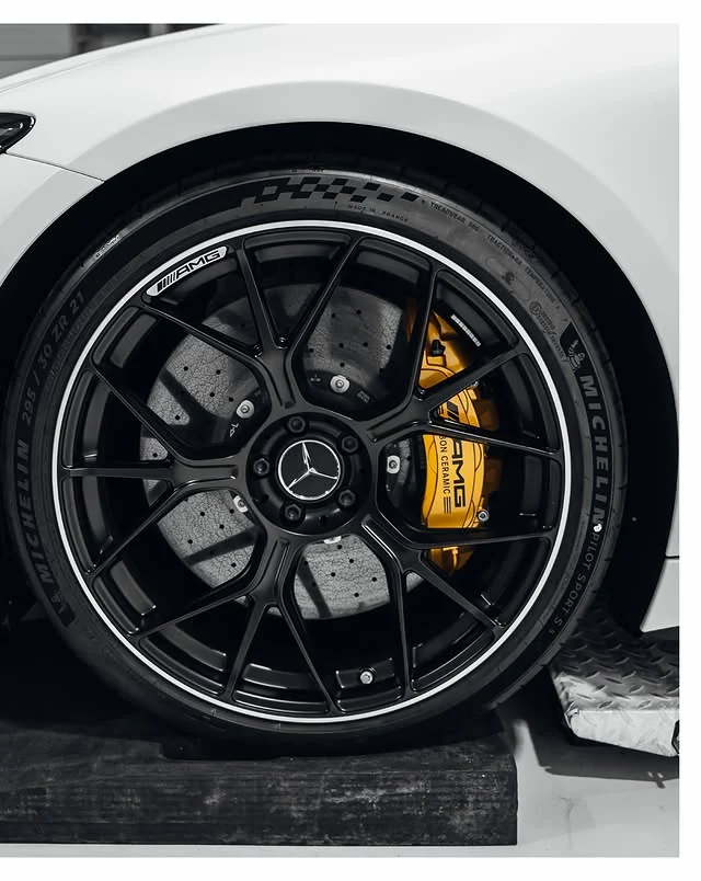 Detailaufnahme von schwarzer AMG-Felge, Reifen und gelbem Bremssattel am weißen GT 63 S