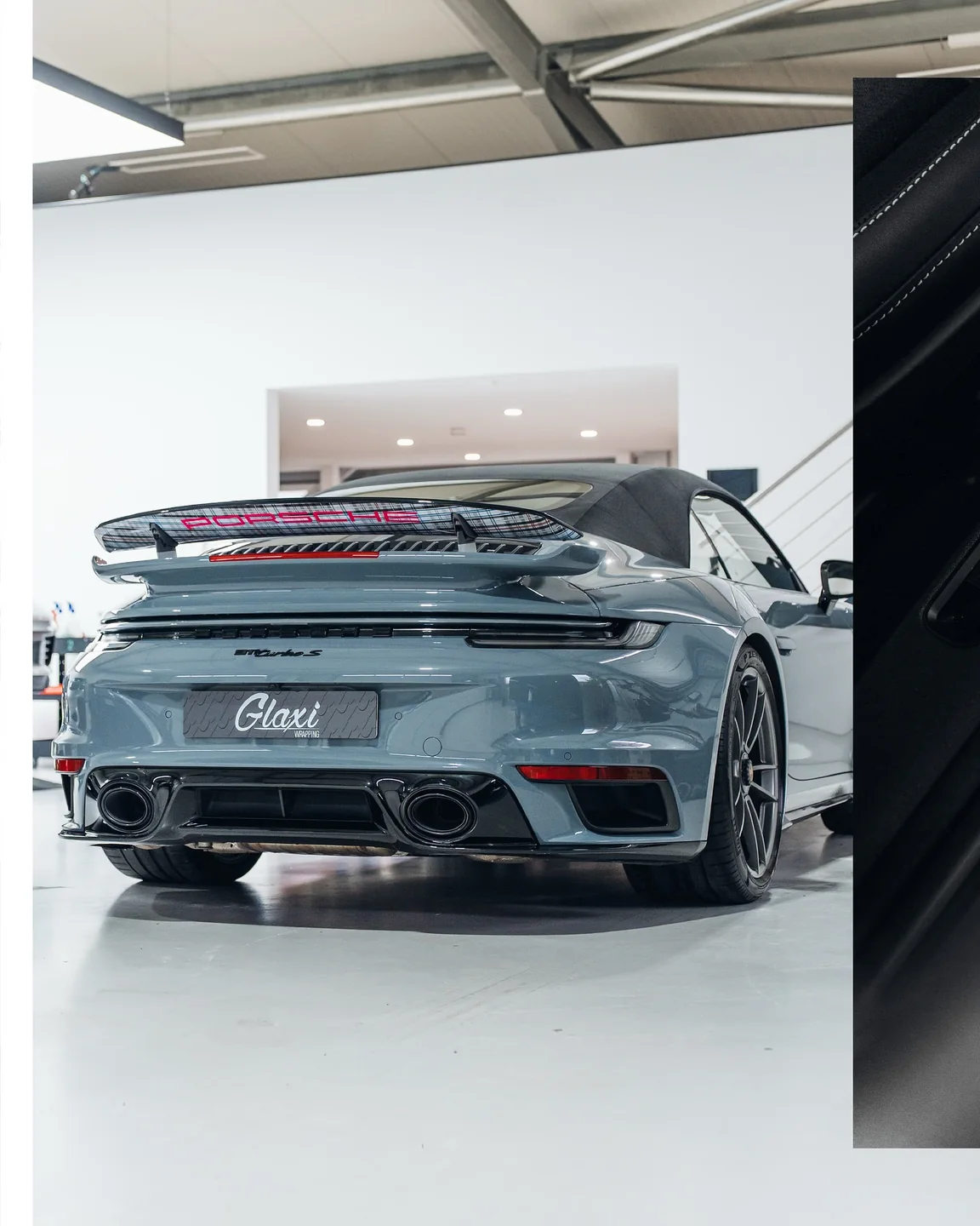 Heckansicht des hellblauen Porsche 911 Turbo S Cabriolet mit ausgefahrenem Heckflügel