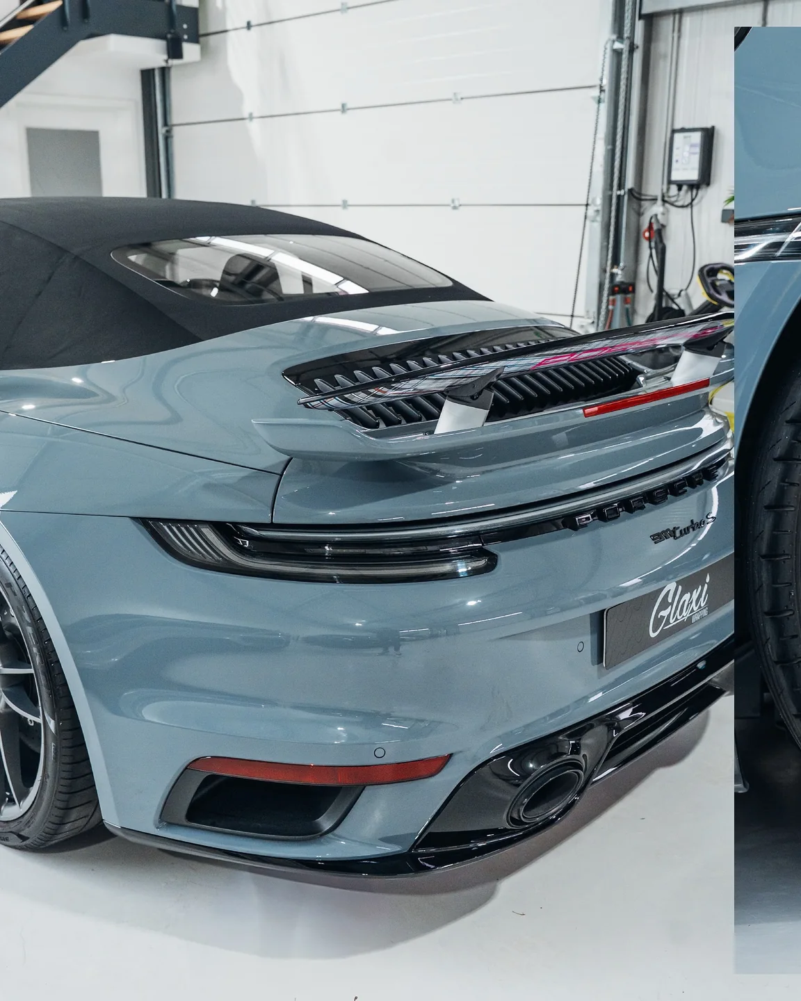 Hellblaues Heck des Porsche Turbo S Cabriolet mit schwarzem Verdeck und ausgefahrenem Spoiler