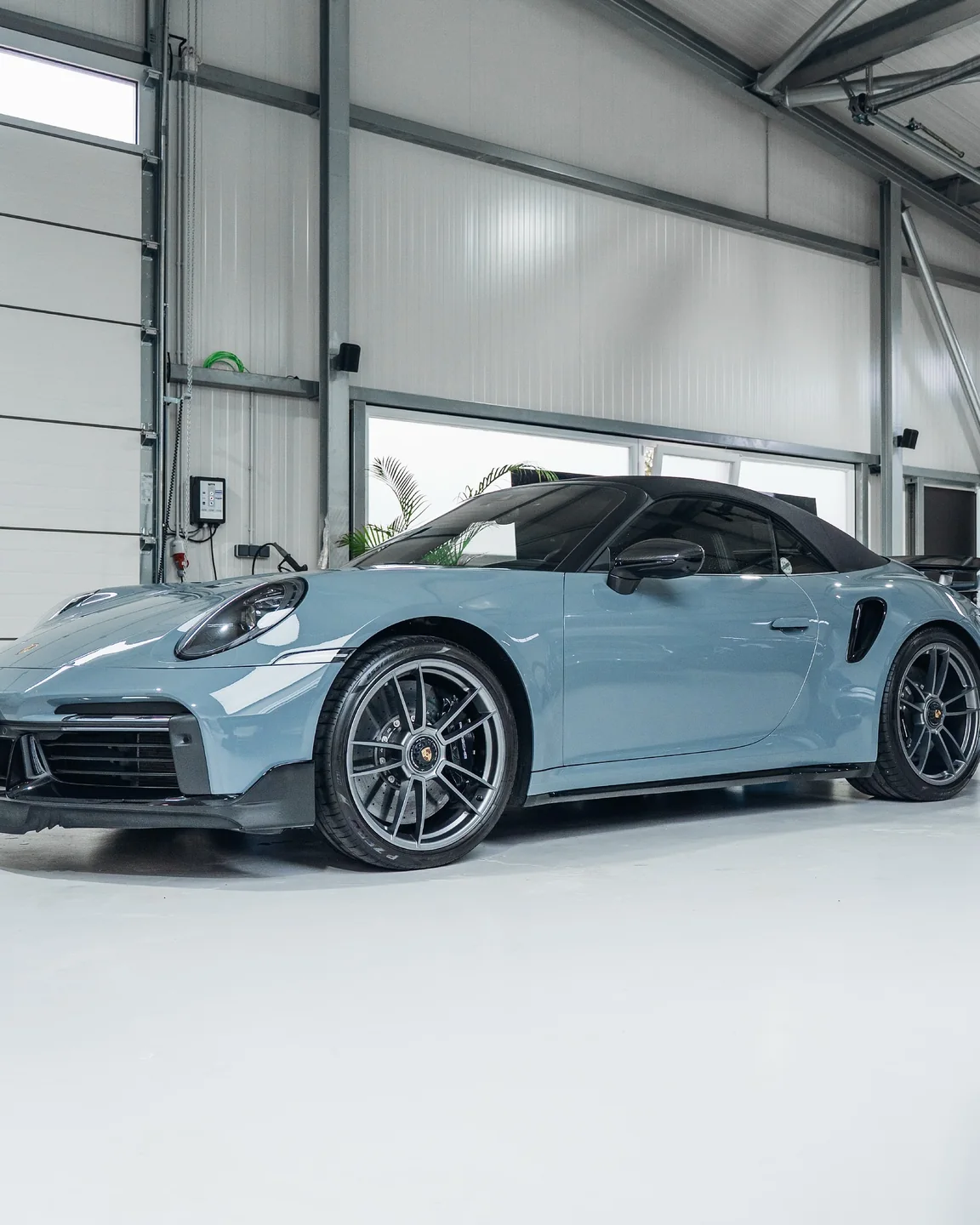 Hellblaues Porsche 911 Turbo S Cabriolet von schräg vorn in der GLAXI-Halle