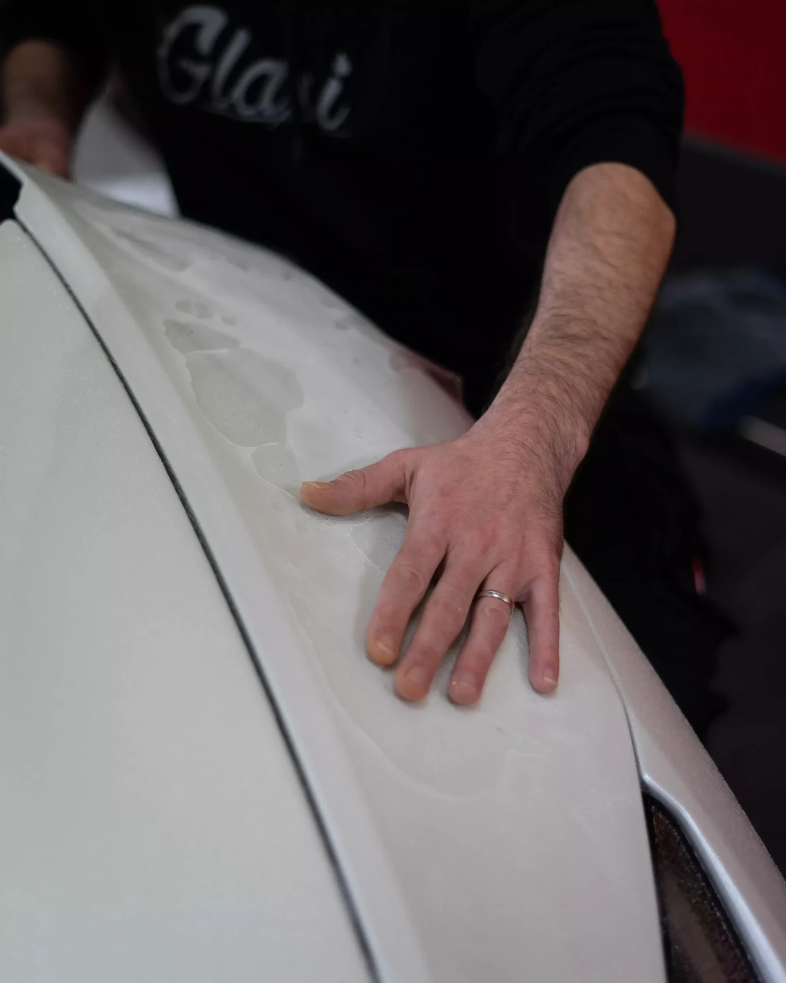 Nahaufnahme einer Hand beim Anlegen transparenter Lackschutzfolie am weißen Lamborghini Huracán Performante
