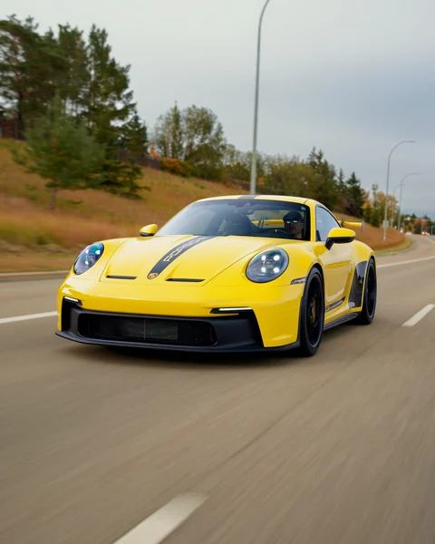 Gelber Porsche 911 GT3 mit dunklem Mittelstreifen während der Fahrt