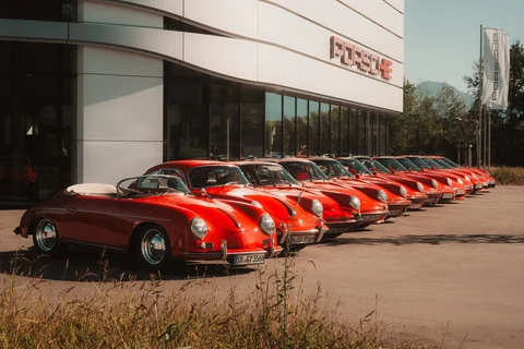 Aufgereihte rote Porsche verschiedener Generationen vor dem Porsche Zentrum Rosenheim, mit einem offenen Klassiker im Vordergrund