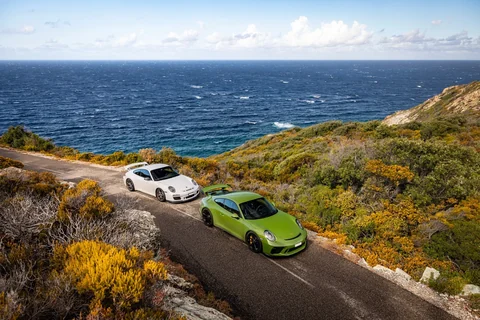 Grüner und weißer Porsche 911 GT3 auf einer Küstenstraße auf Korsika mit Blick auf das Mittelmeer. Originalfoto von @porsche_swissdriver.