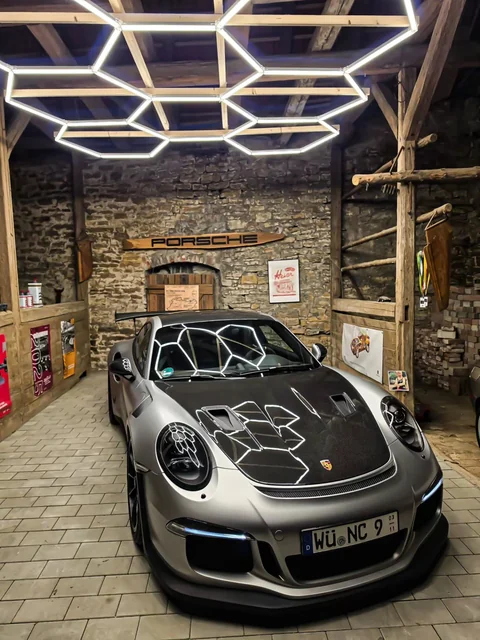 Grauer Porsche 991 GT3 RS in einer rustikalen Garage unter geometrischen Deckenleuchten. Originalbeitrag von @chriss_c7_gt3rs.
