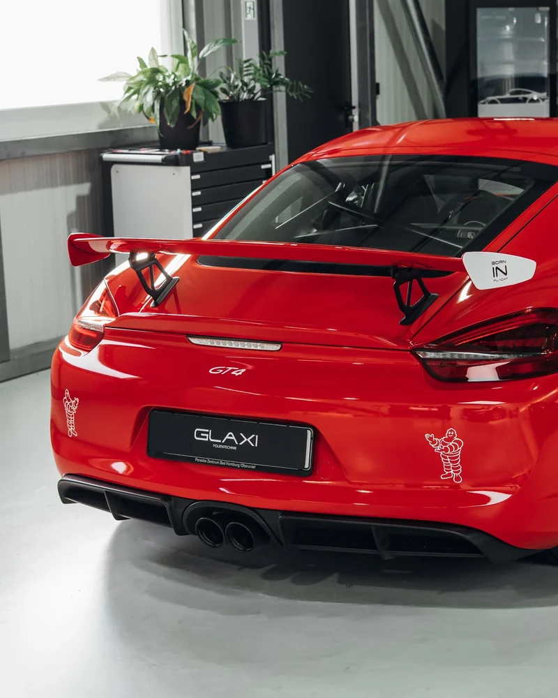 Heck und großer Flügel des roten Porsche Cayman GT4 mit weißen Rennsportdekoren