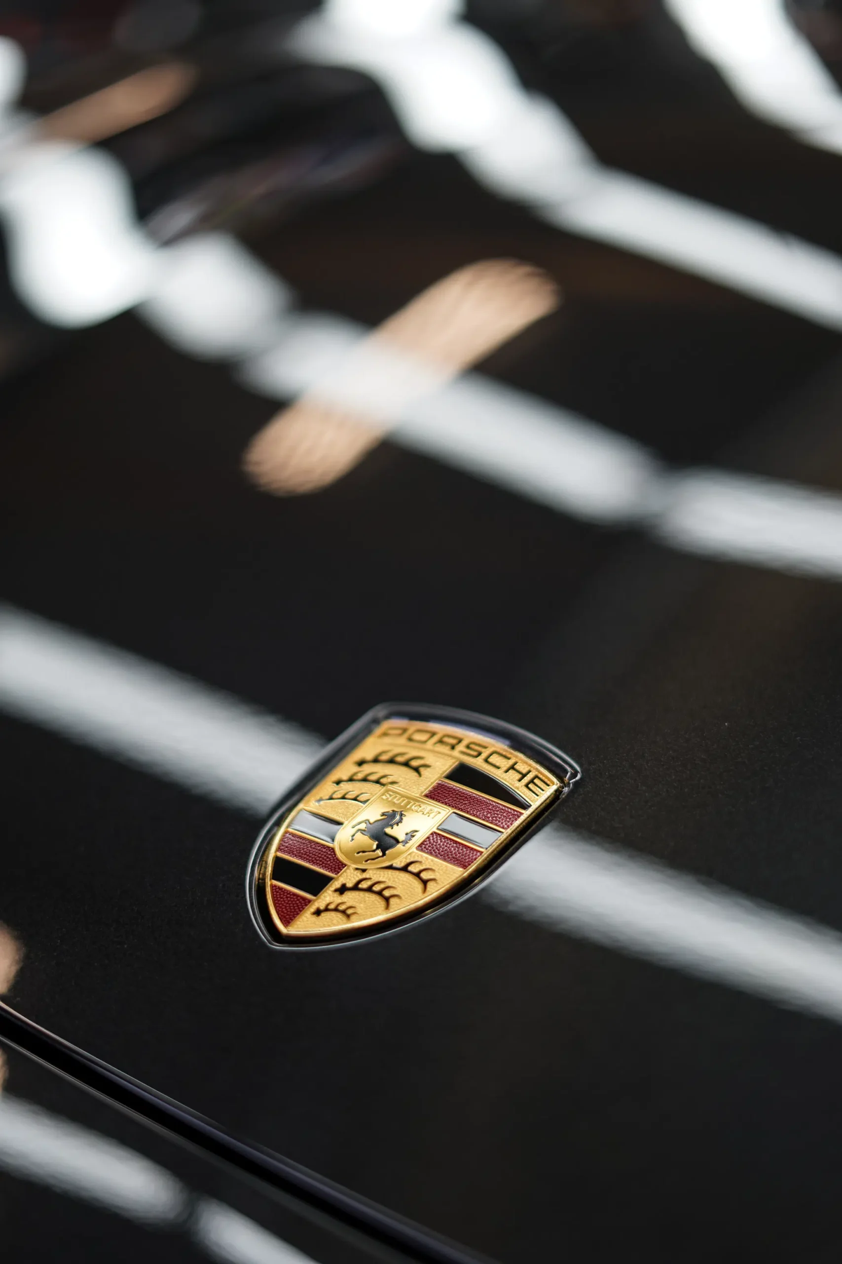 Porsche Logo auf grauer Motorhaube glänzt nach Lackpflege