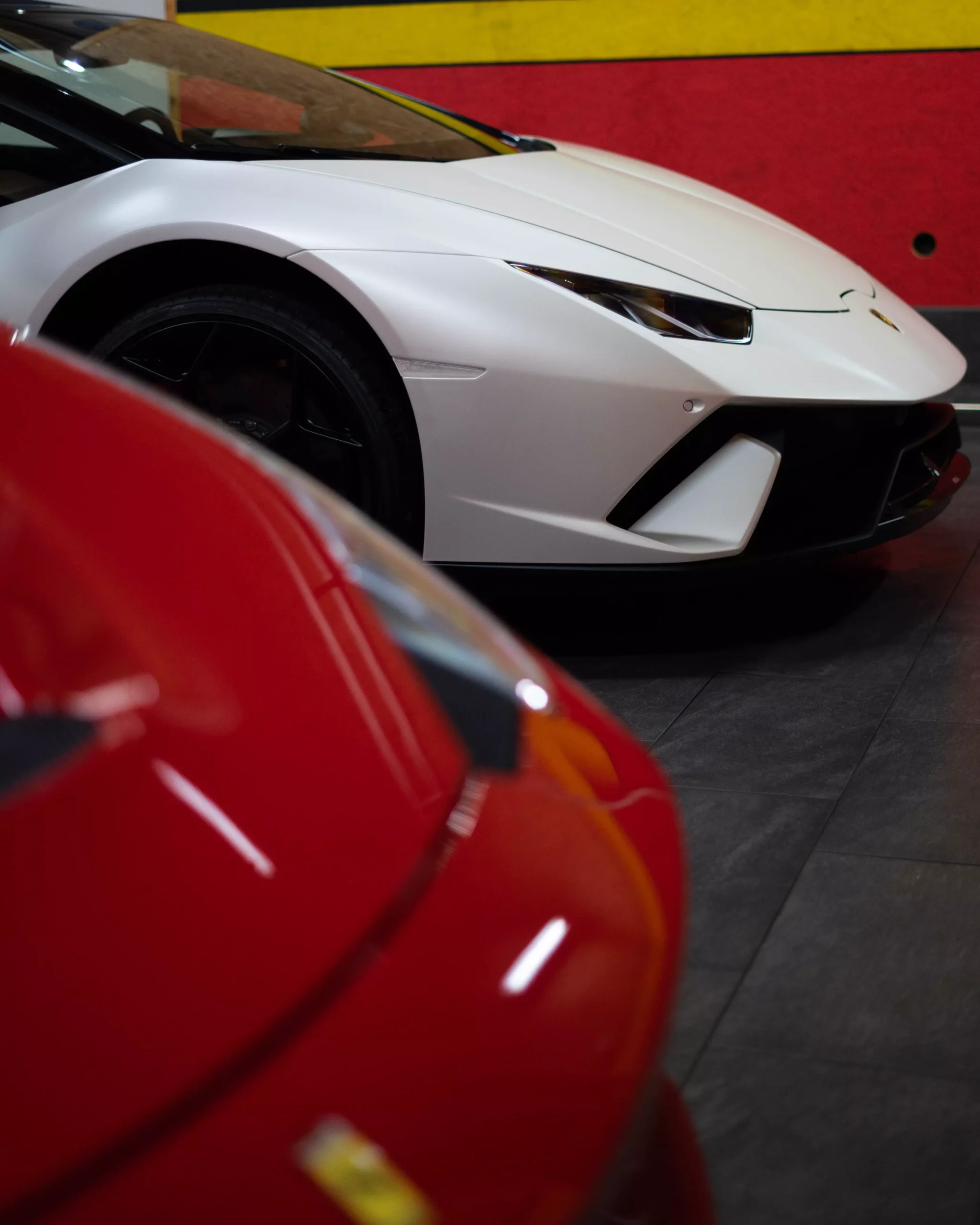 Ein Lamborghini Huracan Performante in weiß matt, der hinter einem Ferrari 458 Sepciale steht.