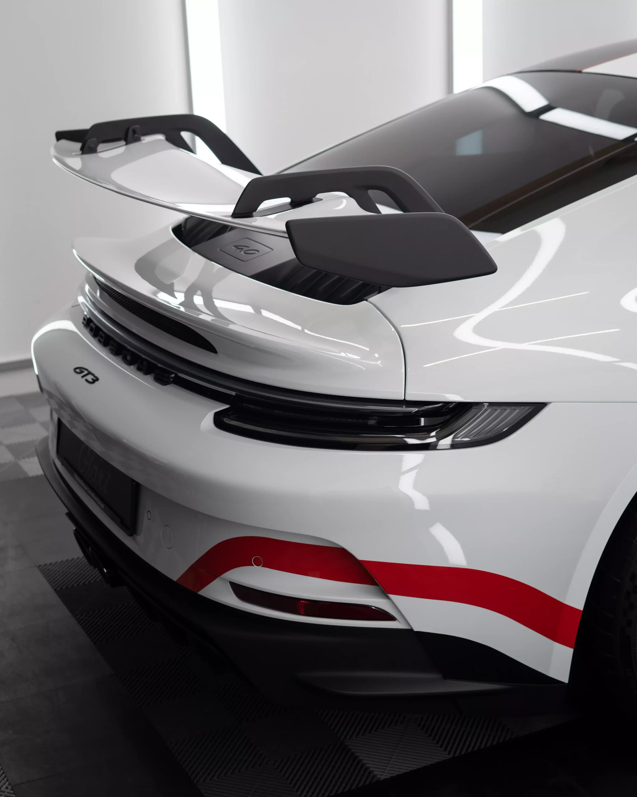Das Bild zeigt einen Porsche 911 992 GT3 mit Designstreifen in rot. Zuvor wurde der Wagen mit Lackschutzfolie foliert. Die Folie glänzt, da im Anschluss eine Keramikversiegelung aufgetragen wurde.