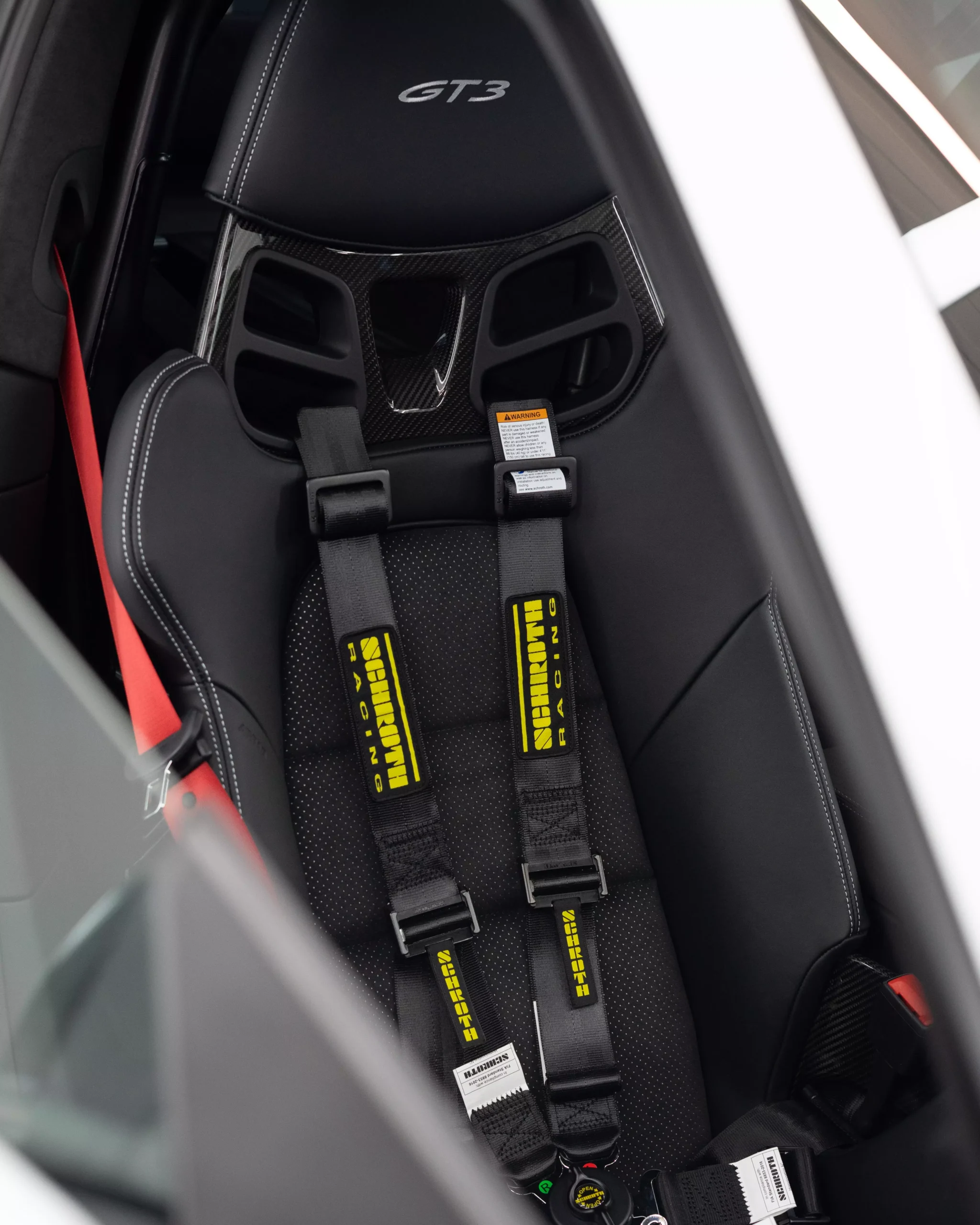 Das Bild zeigt den Innenraum eines Porsche 911 992 GT3 in Carbonschalensitzen und silbernen silbernen Nähten und Schoth Gurten.