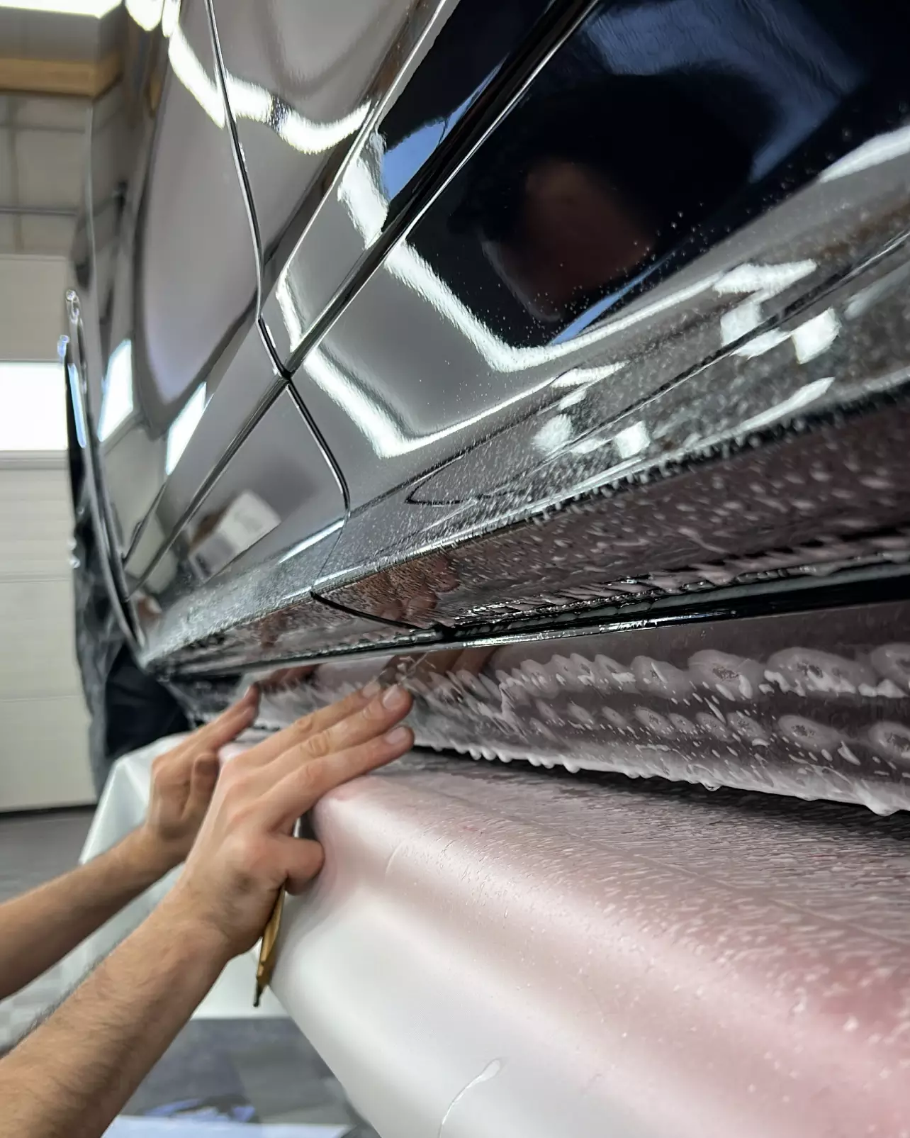 Anbringen der Lackschutzfolie am Schweller eines Porsche Cayenne GTS bei GLAXI in Schwäbisch Hall