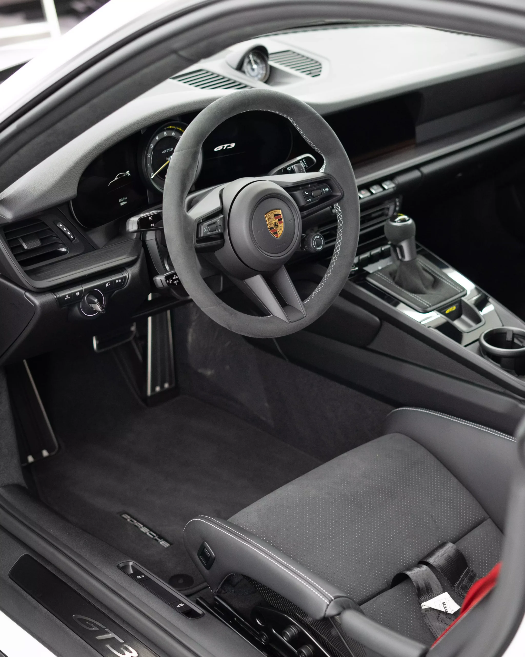 Das Bild zeigt den Innenraum eines Porsche 911 992 GT3 in Carbonschalensitzen und silbernen silbernen Nähten.