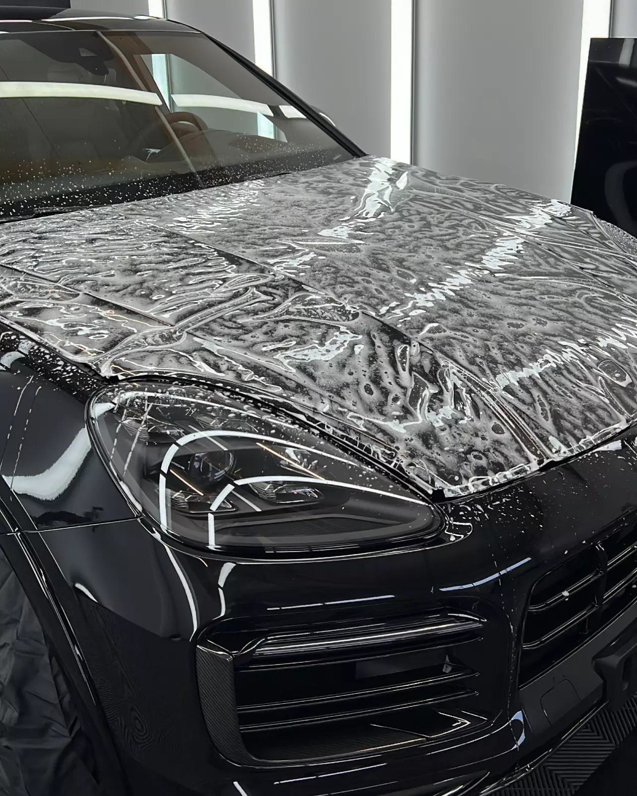 Anbringen der Lackschutzfolie am auf der Motorhaube eines Porsche Cayenne GTS bei GLAXI in Schwäbisch Hall