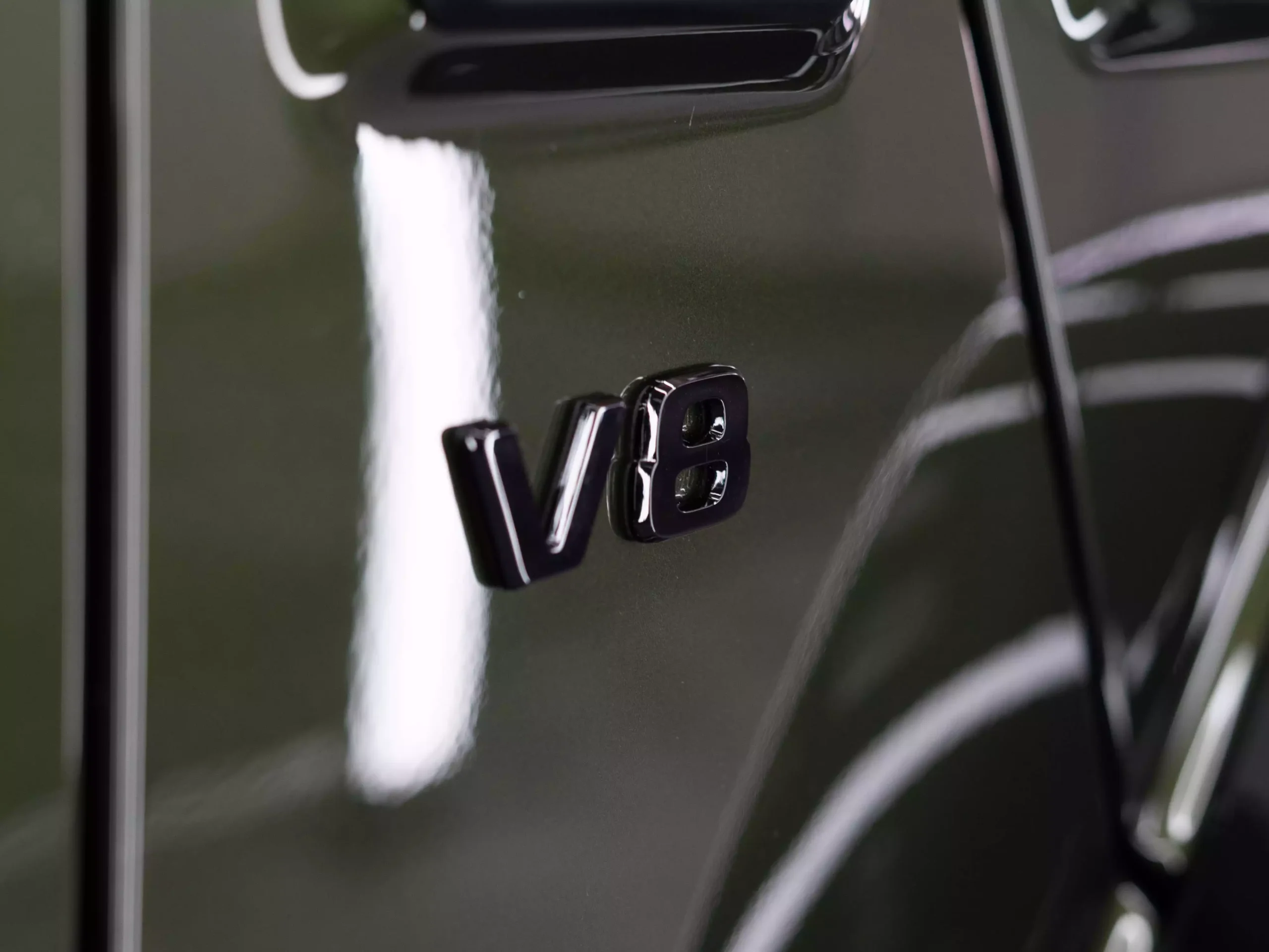 Glänzender, olivfarbener Lack nach der Lackpflege einer Mercedes G-Klasse. Kotflügel rechts mit schwarzem V8 Logo. Der Lack glänzt mit seiner Lackpflege und Keramikversiegelung.